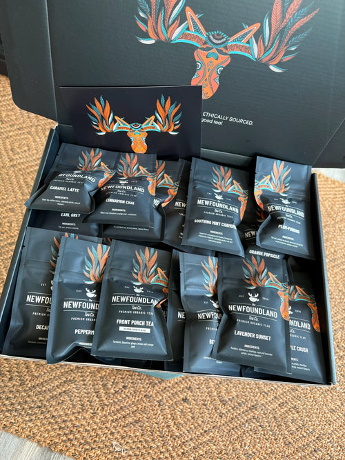 Open All The Blends Box gift box filled with mini loose leaf tea pouches, on a woven rug