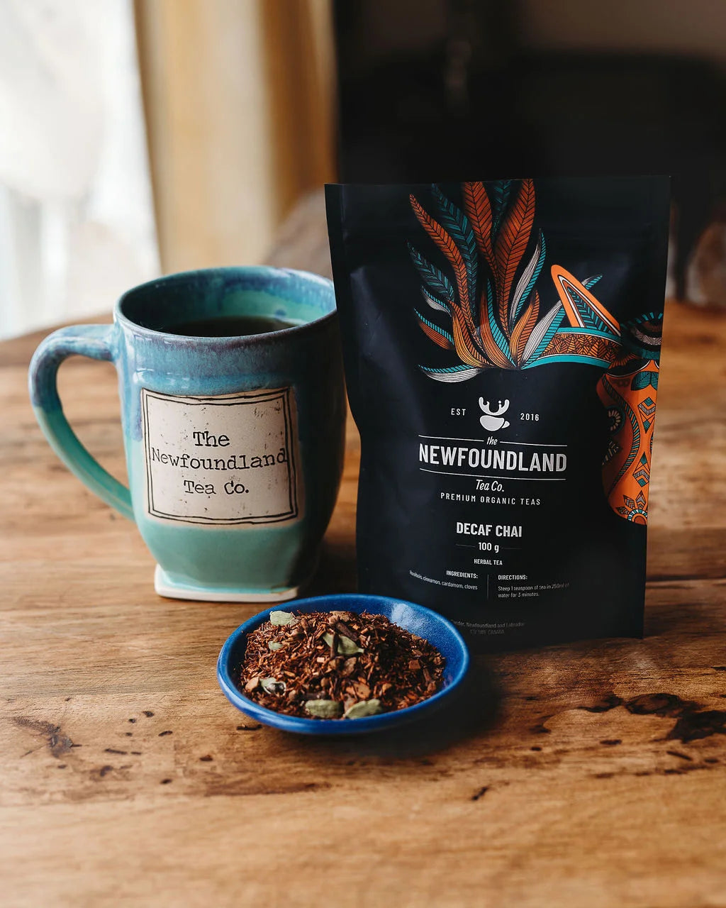 Decaf Chai rooibos tea pouch with a teal Newfoundland Tea Co. mug and loose rooibos with cardamom pods