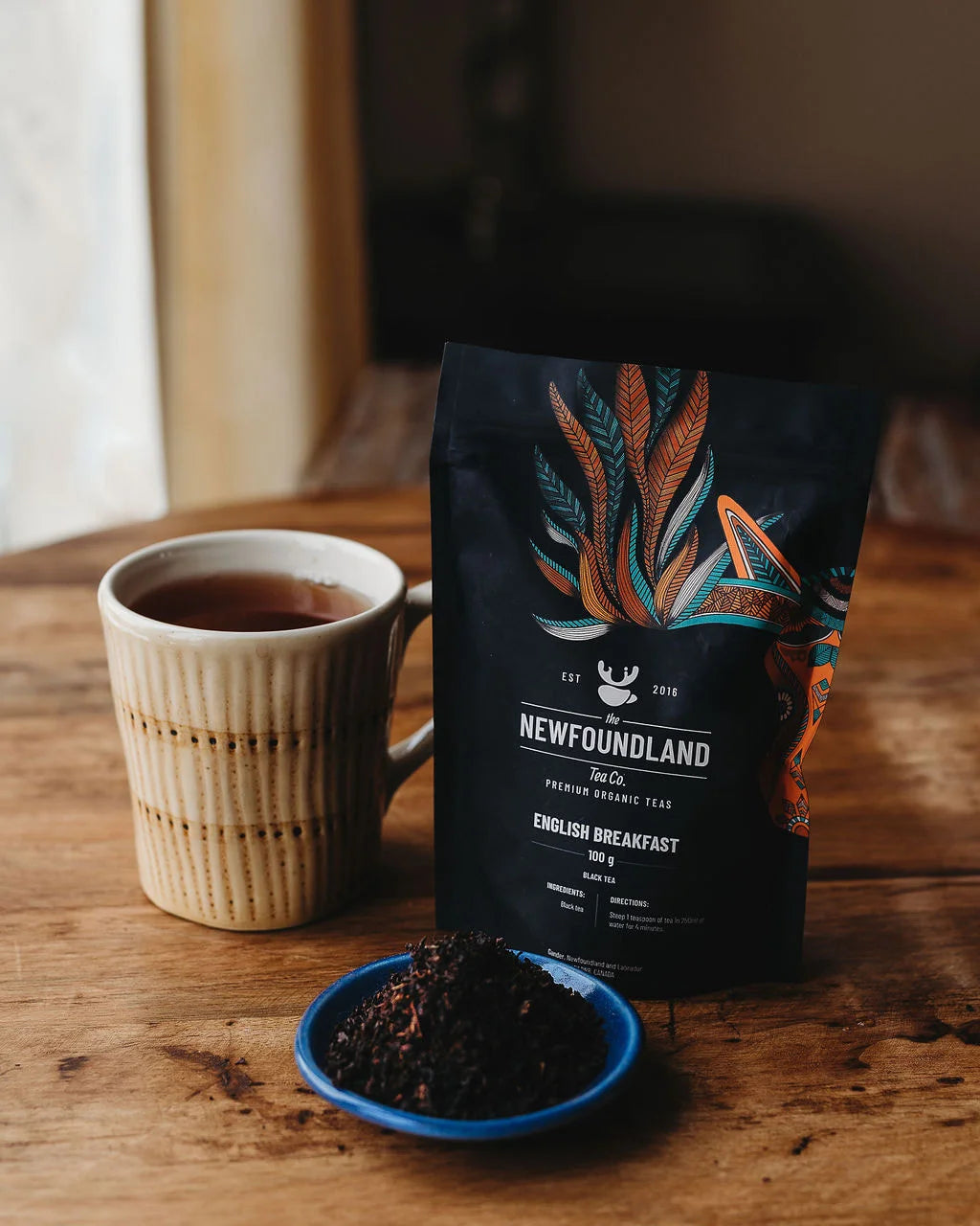 English Breakfast black tea pouch with a ribbed ceramic mug and a dish of loose tea