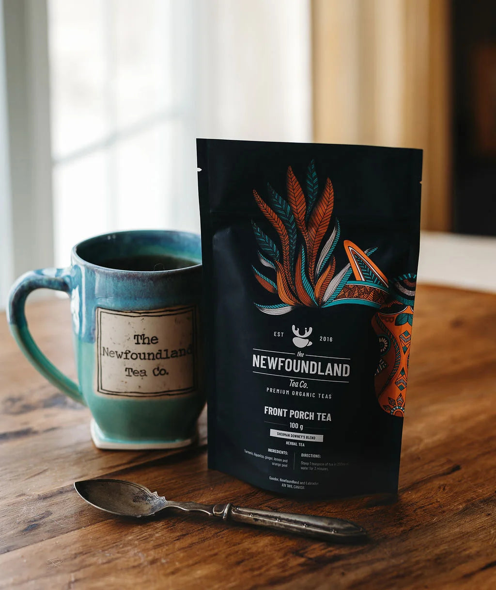 Front Porch Tea, Sherman Downey’s turmeric ginger blend, in a pouch beside a teal mug and spoon